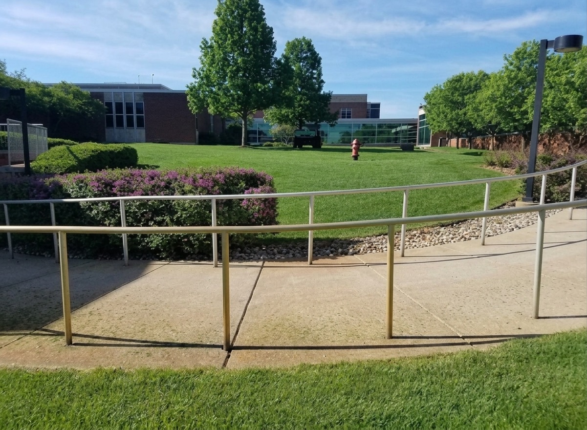 Manicured grounds with shaped beds and a walkway in front of a large building